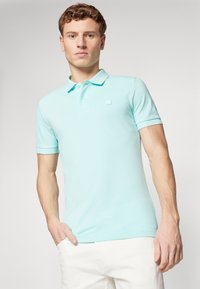 Lyseblå polo skjorte laget av glatt stoff, med krage, korte ermer og en liten logo på brystet. Ingen mønstre eller accenter synlige.