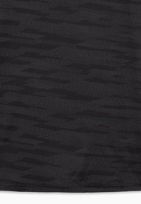 Μαύρο ύφασμα με εναλλασσόμενα σκοτεινά ζιγκ-ζαγκ και σχέδια σε σχήμα κεφάλας βέλους, δημιουργώντας μια υφασμάτινη, αφηρημένη σχεδίαση.