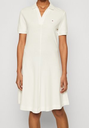 Weißes Polokleid mit kurzen Ärmeln, Kragen und V-Ausschnitt. Weicher Stoff, lockere Passform, mit kleinem gestickten Logo auf der Brust.