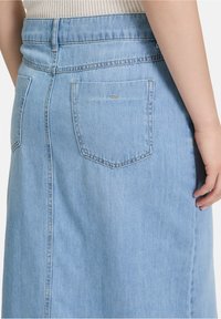 Lichtblauwe denim rok met een achterzak, hoge taille en gestikte naden. Gladde textuur met minimale hardwaredetails.