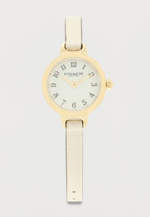 Στρογγυλό ρολόι χειρός Coach σε χρυσό χρώμα με λευκό καντράν, μαύρους αριθμούς, δύο δείκτες και στενό μπεζ δερμάτινο λουράκι.