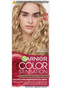 Il packaging della tintura per capelli Garnier Color Sensation presenta una modella con capelli biondo chiaro e ondulati. Il design include accenti rosa e verdi, e il testo mette in risalto il colore a lunga durata.