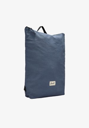 Blauer Stoff-Rucksack mit rechteckiger Form, Reißverschluss, schwarzem Griff und einem kleinen Logo-Patch an der Seite.