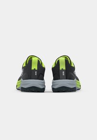 Baskets de sport noires et vert lime avec un dessus texturé, une semelle intermédiaire grise et rembourrée, et une semelle extérieure en caoutchouc durable. La vue arrière met en avant les détails du design.