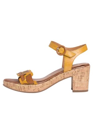 Sandale en cuir jaune et marron avec bride de cheville ajustable, boucle décorative à l'avant et talon bloc en liège épais.