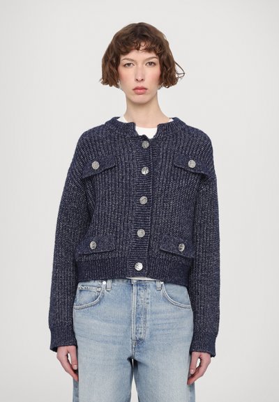 Cardigan en maille bleu marine avec un col rond, des boutons argentés et deux poches avant. Présente un design court et un tissu texturé.