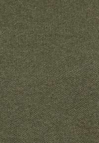 Tessuto lavorato a maglia verde oliva, caratterizzato da una nuova texture a coste fini con cuciture uniformi. Il materiale ha un aspetto morbido e liscio.