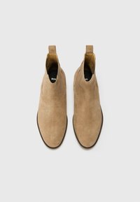 Bottines Chelsea en suède beige avec panneaux élastiques sur les côtés, bout rond et semelle texturée. Intérieur doublé avec un logo sur les semelles.