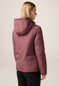 Dunkelrosa Steppjacke mit Kapuze, die eine glatte Textur und ein gesteppte Design aufweist, von hinten vor einem neutralen Hintergrund gezeigt.