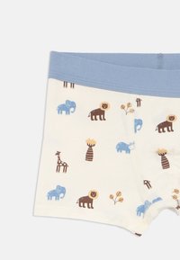 Dětské boxerky s modrým pasem, zdobené kreslenými lvy, slony, žirafami a rostlinami na krémovém pozadí.