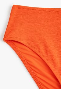 Oranger Bikini-Höschen aus strukturiertem Stoff. Besitzt einen glatten Bund und genähte Nähte, die die lebendige Farbe und das Design hervorheben.