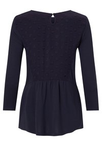 Marinblå tunika med ett texturerat prickmönster på övre ryggen, långa ärmar, nyckelhålsknäppning och utställd nederkant.