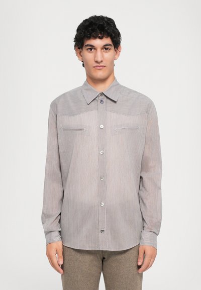 Triibuline nööbitav särk helesinise ja valge keerdusega, millel on pikad varrukad, terav krae ning kaks rinna taskut nööbiga aksessuaare.