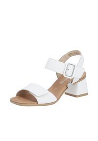 White heeled sandals with a wide toe strap and adjustable ankle strap. Smooth synthetic material, block heel, and decorative buckle detail.