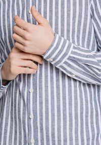 Lichtblauw en wit gestreept overhemd met een knoopsluiting, voorzien van een linnen structuur en zichtbare knopen aan de voorkant en op de manchetten.