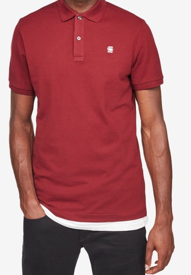 Burgunderröd polo skjorta i bomullstyg, med en tvåknappsslutning, korta ärmar och en liten logga på bröstet.