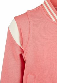 Rosa sweatshirt med vit axelaccent, med en ribbad krage med krämfärgade ränder och en framficka. Mjuk textur, avslappnad design.