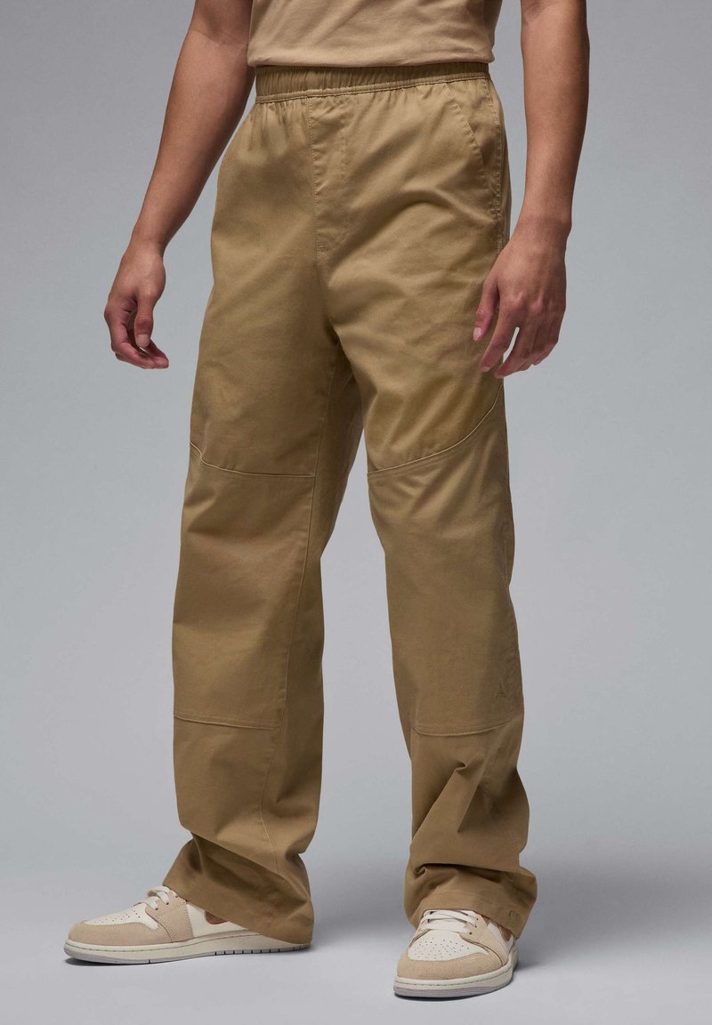 Beige bomulds cargo bukser med elastisk talje og påsyede lommer, der har en afslappet pasform og subtil tekstur. Samlet med beige sneakers.