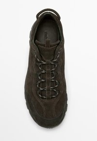 Brauner Wildlederschuh zum Wandern mit strukturierter Oberfläche, sechs Ösen, dunklen Schnürsenkeln und gepolstertem Schaft. Gummisohle mit Profil. Kein sichtbares Branding.