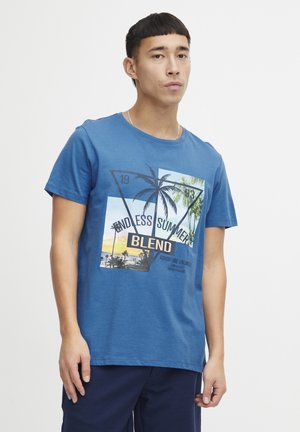 Plava pamučna majica s grafičkim dizajnom koji prikazuje palme, natpis "BEZKRAJNO Ljeto" i prizor zalaska sunca na plaži. Kratki rukavi, okrugli izrez.