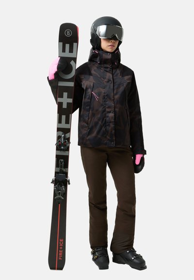 Schwarze Camouflage-Skijacke, braune Skihosen, rosa Handschuhe, schwarze Skischuhe und Ski mit roten Akzenten. Eine Skibrille und ein Helm runden das Outfit ab.