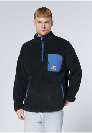 Black fleece pullover with zip collar, contrasting blue chest pocket, and embroidered logo. Soft texture and long sleeves.