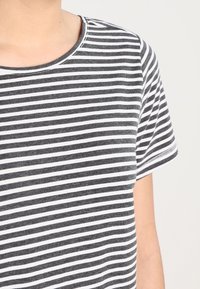 Camiseta a rayas con rayas horizontales en blanco y negro, escote redondo, mangas cortas y una textura de tela suave.