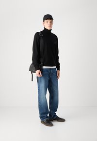 Črna rolka, svetlo modri jeans, črna kapa in črna torbica čez telo. Tenisice imajo teksturirane podrobnosti. Enostavna ozadja.