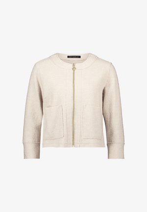 Jasno beżowa kurtka zapinana na zamek, wykonana z teksturowanej tkaniny, z okrągłym kołnierzem, dwiema przednimi kieszeniami i złotym zamkiem błyskawicznym.