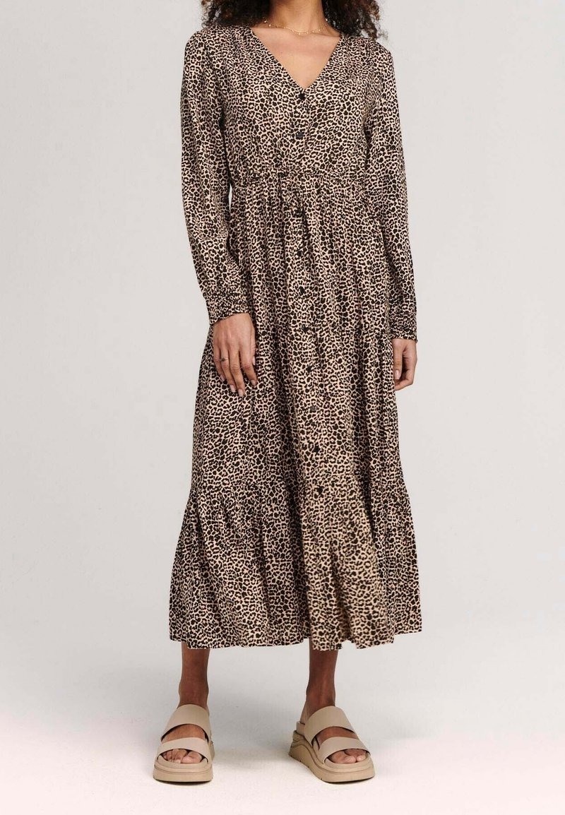 Långärmad klänning med leopardmönster, V-ringning, insvängd midja och lager på lager-skirt. Mjuk tyg med en naturlig beige och brun färgskala.