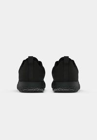 Black athletic shoes featuring a smooth, textured upper, pull tabs, and a flexible rubber sole with a patterned tread for grip.