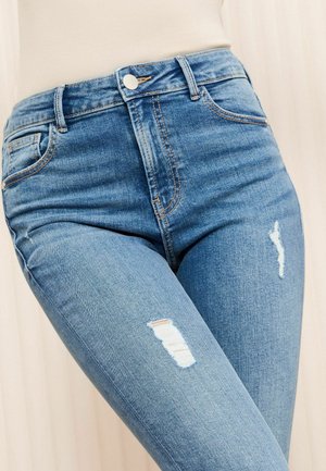 Jeans in denim blu a vita alta con leggeri strappi sul davanti, cuciture a contrasto e design classico a cinque tasche.