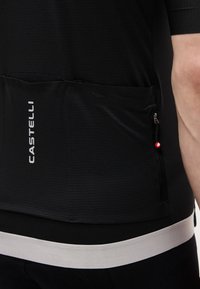 Μαύρη ποδηλατική φανέλα με τρεις πίσω τσέπες, λευκή ανακλαστική ταινία στο τελείωμα, λογότυπο Castelli και τσέπη με φερμουάρ στη δεξιά πλευρά.