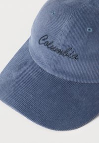 Μπλε καπέλο από κορδούρα με κεντημένο λογότυπο "Columbia" στο μπροστινό πάνελ, με ραμμένες τρύπες αερισμού και καμπυλωτό γείσο.