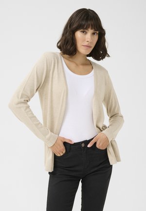 Beige cardigan with an open front, long sleeves, and a soft texture, worn over a white top and black pants. Simple, minimalist design.