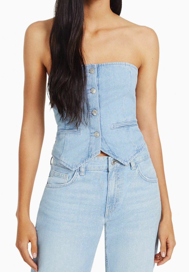 Ljust blå denimstrapless topp med knapplist fram, figursydd design och subtila sömnadsdetaljer längs sömmarna.