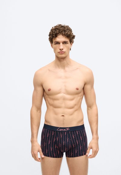 Fekete boxeralsó ismétlődő piros "love" mintával, elasztikus derékrésszel, amelyen "Love" logó található, testhezálló kialakítás, puha anyag, középhosszúságú combig érő fazon.