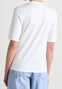 White short-sleeve t-shirt with a round neckline, made of soft cotton, featuring a smooth texture and clean lines without additional decorations.
