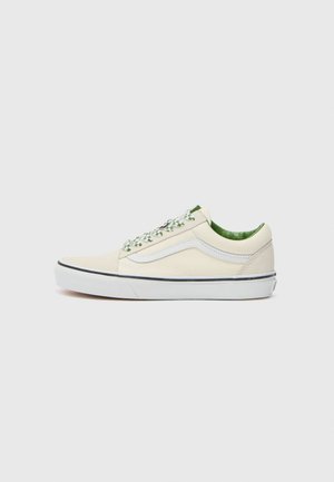 Beige canvas low-top sneaker with green accents, white rubber sole, and patterned laces. Features a side stripe design.