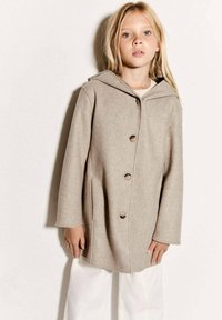 Beige kabát z vlněné směsi s kapucí, volného střihu, dlouhými rukávy a čtyřmi velkými knoflíky na přední straně. Čisté linie a minimalistický design.