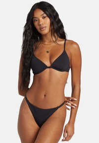 Černý bikini set s tenkým trojúhelníkovým topem s nastavitelnými ramínky a spodním dílem s nízkým pasem. Hladká textura, minimalistický design, žádné vzory.