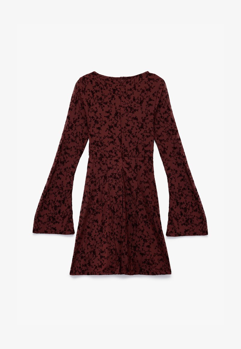 Burgundin mekko, jossa on pitkät kellohihat ja musta kukkakuosi. Valmistettu teksturoidusta kankaasta, sillä on istuva vyötärö ja takasauma.