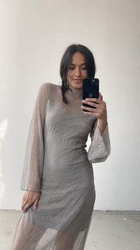 Vestido transparente de mangas compridas em cinza claro com textura floral. Decote alto, silhueta ajustada e mangas abertas. Detalhe em tecido refletivo.