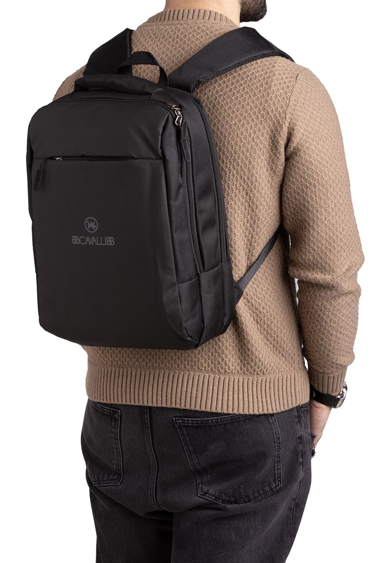 Zwarte nylon rugzak met verstelbare schouderbanden, een voorvak met rits en een gevoerde achterkant. Kenmerkt zich door een gladde textuur en een logo op het voorpaneel.