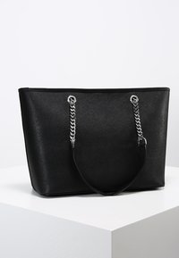 Borsa tote nera realizzata in materiale sintetico strutturato. Presenta manici a catena color argento e un design rettangolare spazioso.