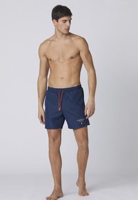 Costumi da bagno blu navy con vita elastica e cordino arancione, con discreto logo sul lato sinistro inferiore.