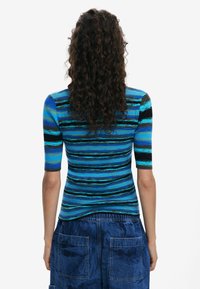 Blue striped knit top with short sleeves, featuring varying shades of blue, black, and turquoise. Fitted design with ribbed texture.
