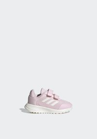 Zapatilla deportiva rosa con parte superior de malla y superposiciones sintéticas. Presenta dos correas de gancho y bucle y acentos blancos en el lado. Suela flexible.