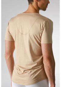 Beżowa koszulka z krótkim rękawem, okrągłym dekoltem, charakteryzująca się gładką bawełnianą teksturą oraz zaokrągloną linią szwu z tyłu.