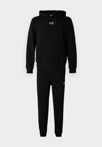 Conjunto de sudadera y pantalones de chándal negros hechos de algodón, con capucha, puños elásticos y un logo en el pecho y la pierna. Textura suave.